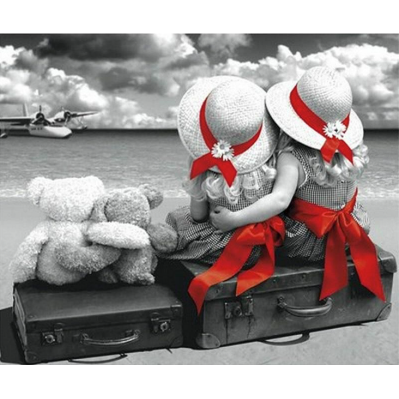 "2 piger med bamser" i Diamond Paint, viser to piger iført kjoler og matchende røde sløjfer, der omfavner hinanden på en kuffert ved vandkanten. Ved deres side er deres elskede bamser,