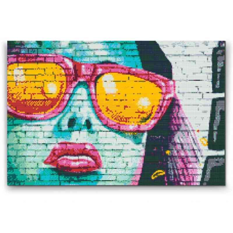 En strålende diamond art-gengivelse af en kvinde med lyserøde briller, fortryllet af en farverig graffiti-effekt. Bestil hos 5D Diamond Paint.